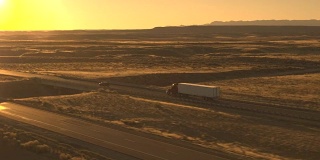空中汽车在公路上行驶，在日落时超过乡村公路上行驶的卡车