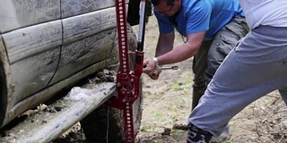 两名旅行者在森林肮脏的道路上更换了探险SUV的车轮。