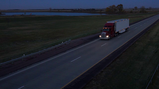 空中摄影:夜间在路上用集装箱运输货物的半挂车