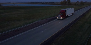 空中摄影:夜间在路上用集装箱运输货物的半挂车