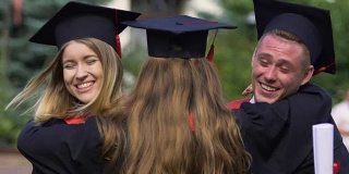 毕业同学们的脸上挂着幸福的学位服，朋友们拥抱着