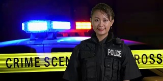亚裔美国女警官对着镜头微笑，背景是犯罪现场