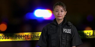亚裔美国女警察微笑着在犯罪现场与警报器的背景，垃圾摇滚的样子