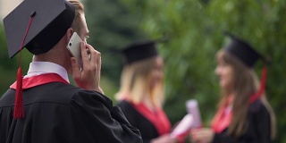 快乐的男毕业生聊着手机笑着，毕业的日子