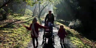 活跃的家庭散步在冬季公园在明亮的阳光和寒冷的日子，他们呼吸蒸汽