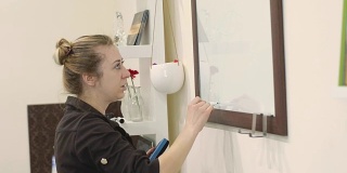 专业化妆师在大师班上教授化妆技巧。严肃的女老师用绿色记号笔在一块玻璃板上画了一条线。