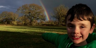 小男孩兴奋地发现了美丽的彩虹，并指向它