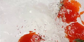 几个红色的西红柿掉进水里。白色背景