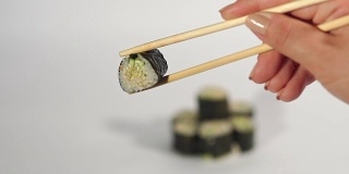 手拿寿司卷在筷子里，白白的bg。
