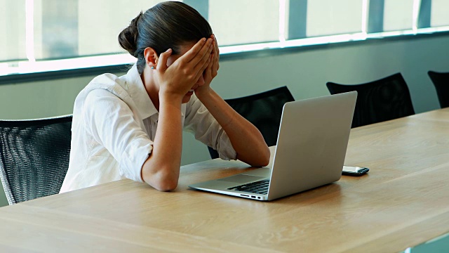 一位高管在会议室用笔记本电脑工作时哭泣