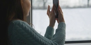 小女孩在火车上旅行，用手机拍下窗外的风景。美女用智能手机拍照。近距离