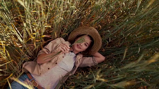 年轻的女农民躺在麦田里的小麦中休息
