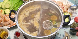 概念火锅亚洲美食。将虾分配到撇子中煮。妻子照顾丈夫