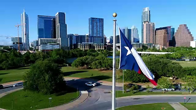 围绕德克萨斯旗在完美的旗杆与奥斯汀德克萨斯天际线城市景观在背景