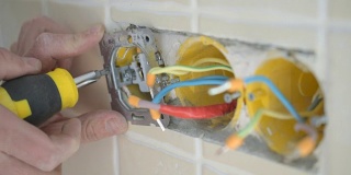 电工双手安装电线插头到墙上