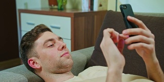 躺在沙发上玩手机的男人