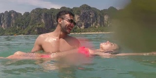 一名男子抱着一名女子在海水里游泳