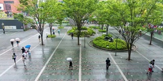 人们在雨中行走在城市广场的时间流逝