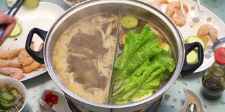 概念火锅亚洲美食。沙拉，西葫芦，虾放入沸腾的肉汤中，用筷子烹饪