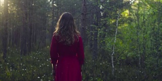 穿着红衣服的年轻女子在森林里散步