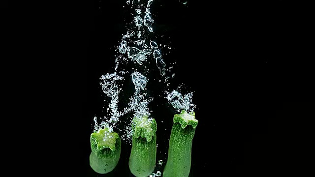 长西葫芦或西葫芦，瓜派，蔬菜落入水中的黑色背景，慢镜头4K