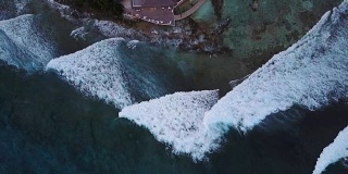 俯瞰马尔代夫岛，相机正在上升的酒吧在豪华热带酒店度假。无人机在餐厅上方显示巨大的海浪。飞溅的航拍画面
