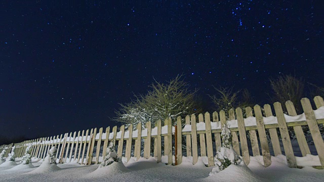 夜空星星时光流逝，房子后院的木栅栏前景