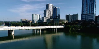 美国德克萨斯州奥斯汀市的第一街桥，矗立在城镇湖上，倒影着新市中心的建筑和摩天大楼