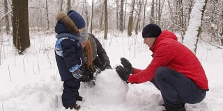 一家人和孩子们在公园堆雪人。