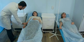 男医生检查两名女病人在床上点滴休息
