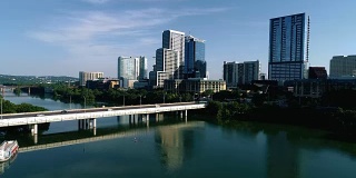 走向美国德克萨斯州奥斯汀市的第一街桥，从城镇湖上直起，映照着新市中心的建筑和摩天大楼