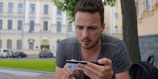 男子用信用卡在网上购物时用智能手机在公园的长椅上