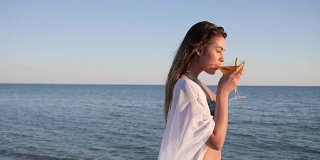 性感女孩沿着海滩模特，夏天在海上休息，年轻女性喝鸡尾酒