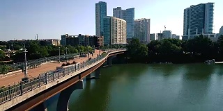 步行桥清晨无人机在城镇湖与奥斯汀德克萨斯市中心摩天大楼的背景和慢跑者，骑自行车的人，行人享受夏天的早晨