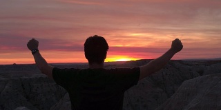 成功的人站在山顶，夕阳西下，向天举起手臂