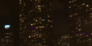 低角度视角:揭示了高大的现代玻璃住宅摩天大楼在晚上点亮