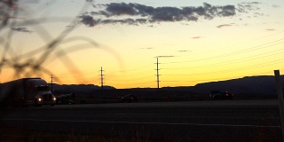 慢镜头:日落时分，汽车和半挂车在犹他州乡间行驶