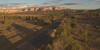 空中黑色SUV汽车沿着空荡的道路驶向犹他州的mesa山