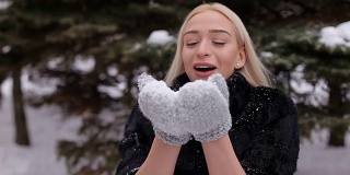 美丽的女孩吹在雪地上的特写镜头。