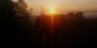 清晨的路上。从火车窗口望出去的景色——冉冉升起的太阳，山谷里的树木和雾气