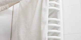 女人把白毛巾挂在衣架上
