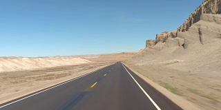 FPV:驾驶沿着空的道路通过灰色的沙漠峡谷在犹他州，美国
