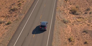 一辆黑色SUV行驶在沙漠中空旷的道路上