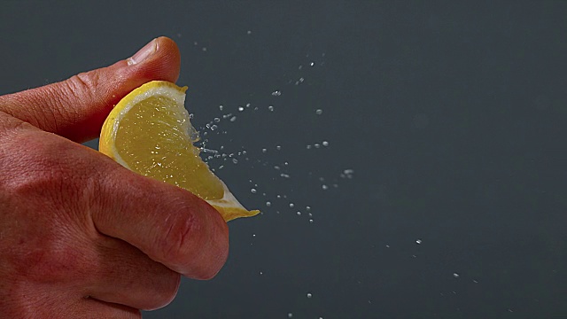 手挤柠檬，柑橘柠檬对黑色背景，慢镜头4K