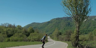 一个年轻人骑着回旋滑板车行驶在乡间的道路上