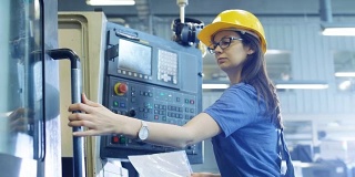 专业的女操作员在控制面板的帮助下设置/编程数控机床。可见大工业工厂。