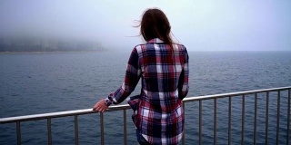 风平浪静的女人回头望海。女人的背影看在雾海洋