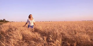 慢镜头中，一名年轻女子微笑着沿着乌克兰的麦田奔跑