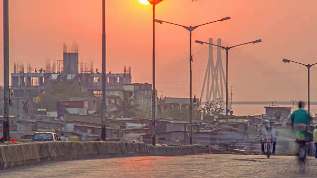 在印度孟买，夕阳西下的班德拉沃里海，也被称为拉吉夫甘地海，同时移动的交通和行人在前景