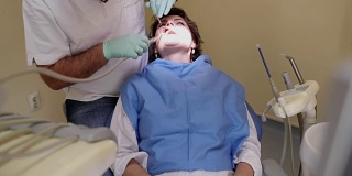 牙医在检查一个女人的牙齿，手持枪